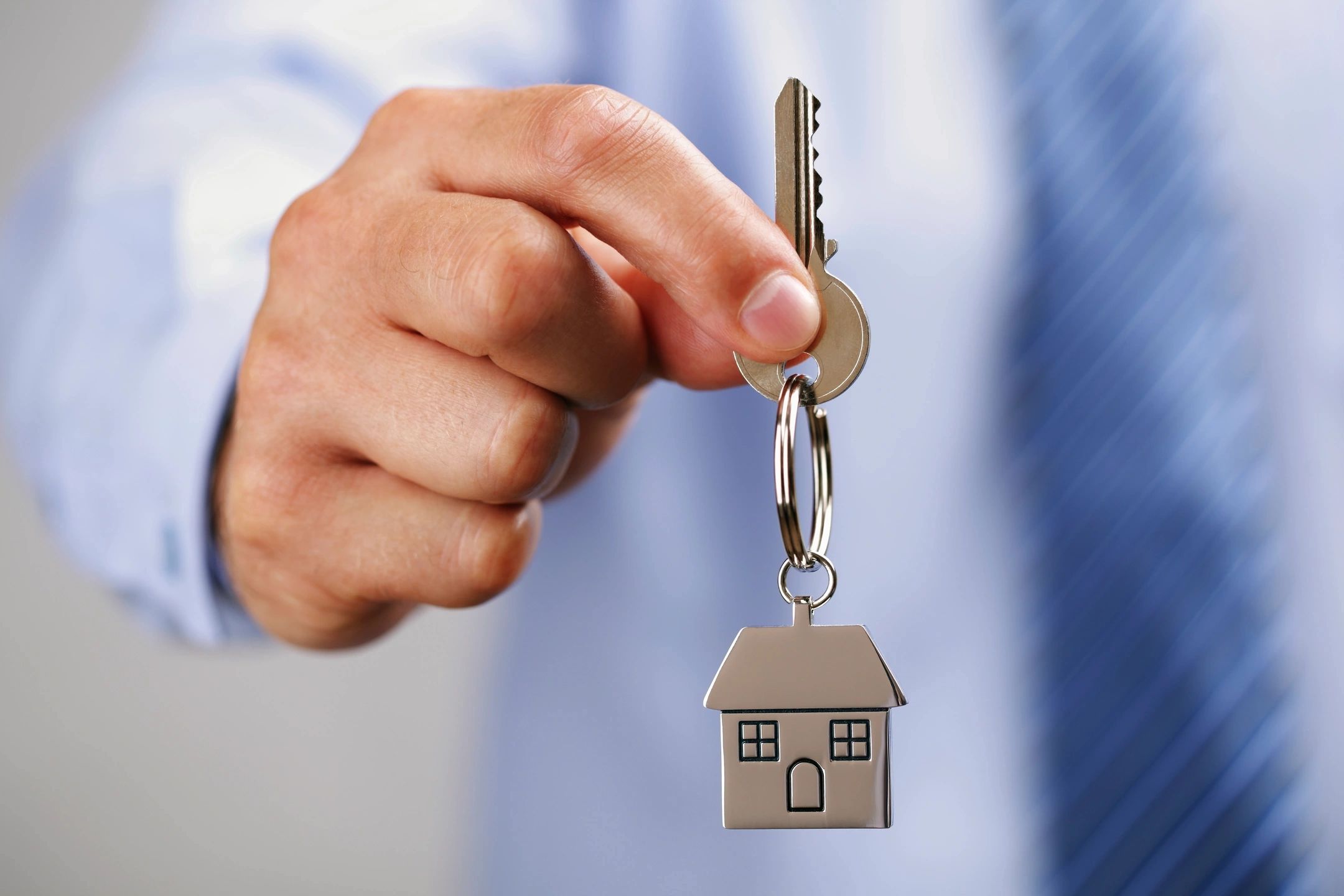 Person holding house key with house emblem