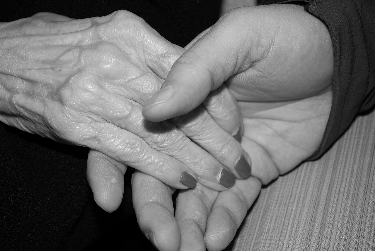 An older adult and younger adult hold hands